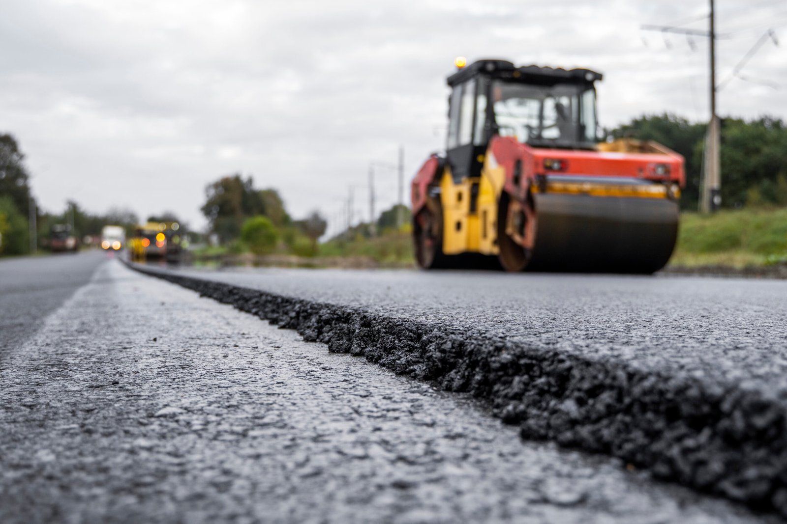 Asphalt road roller with heavy vibration roller compactor press new hot asphalt on the roadway on a road construction site. Heavy Vibration roller at asphalt pavement working. Repairing